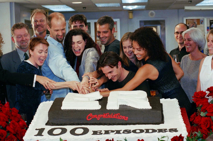 I membri del cast di "ER", da sinistra a destra: Laura Innes, Anthony Edwards, Julianna Margulies, George Clooney, Noah Wyle, Kellie Martin e Gloria Ruben tagliano una torta per festeggiare il centesimo episodio della serie televisiva di successo della NBC sul set dei Warner Brothers Studios a Los Angeles, il 20 ottobre 1998. Nella seconda fila, da sinistra a destra, sono ritratti anche il presidente della NBC Warren Littlefield e il creatore della serie John Wells. L’uomo alle spalle di Margulies non è stato identificato. (Foto AP/Rene Macura) (ASSOCIATED PRESS)