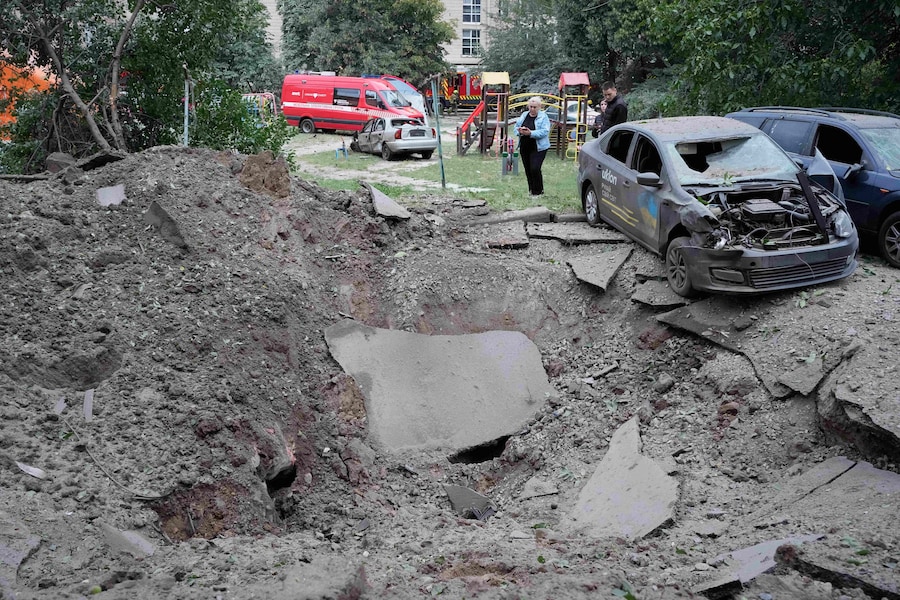 Lunedì 6 luglio 2026, alcuni residenti si trovano nei pressi di un cratere e di alcune auto danneggiate dall'attacco missilistico russo a Kiev, in Ucraina. (AP Photo/Efrem Lukatsky/Associated Press/LaPresse/APN)