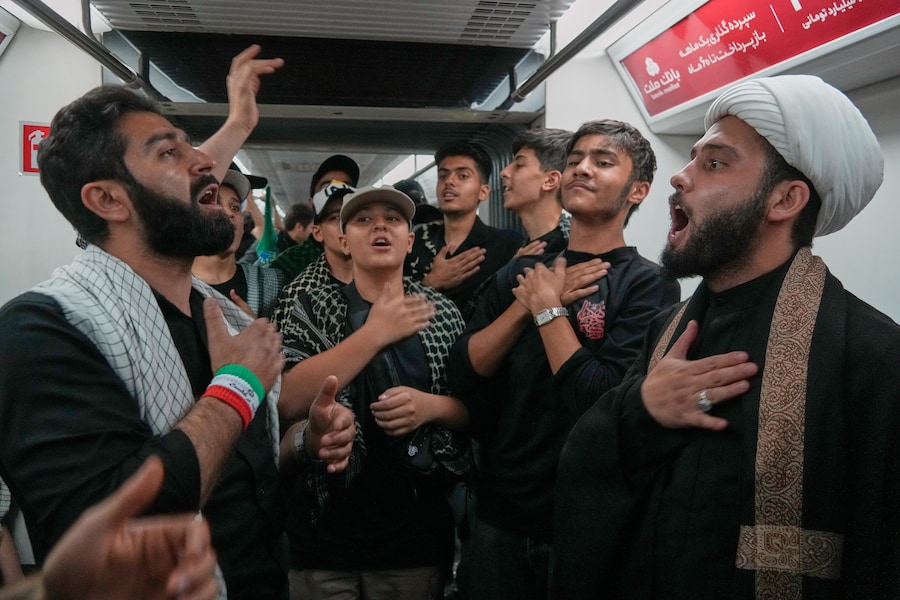 Alcuni uomini si battono il petto a bordo di un treno della metropolitana mentre si recano al corteo funebre. Teheran, Iran. (APN)