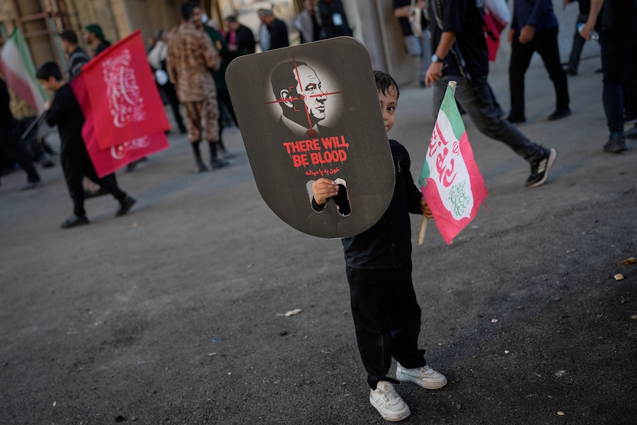 Un ragazzo sbircia da dietro un cartello raffigurante il primo ministro israeliano Benjamin Netanyahu, su cui sono riportati un mirino e la scritta “Ci sarà sangue”, durante le cerimonie funebri per il leader supremo iraniano assassinato, l’ayatollah Ali Khamenei. Teheran, Iran. (APN)