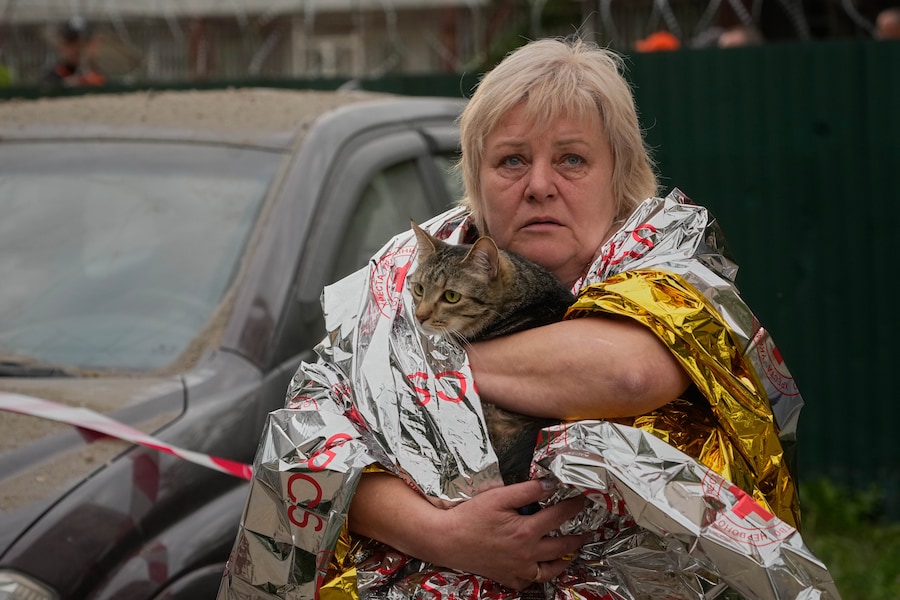 Una donna porta fuori il proprio gatto da un condominio a più piani danneggiato in seguito a un attacco missilistico russo a Kiev. (APN)