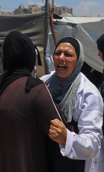 Una donna osserva mentre alcuni palestinesi ispezionano il luogo in cui un attacco israeliano ha colpito una tenda in un campo che ospita sfollati, nella città di Gaza, il 7 luglio 2026. REUTERS/Ebrahim Hajjaj (REUTERS)