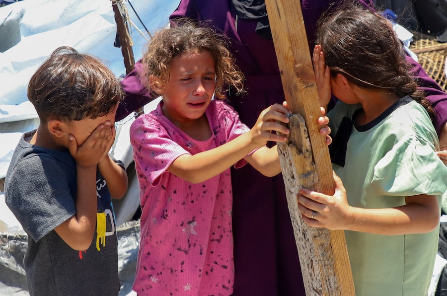 I bambini reagiscono mentre i palestinesi ispezionano il luogo in cui un attacco israeliano ha colpito una tenda in un campo che ospita sfollati, nella città di Gaza, il 7 luglio 2026. REUTERS/Ebrahim Hajjaj (REUTERS)