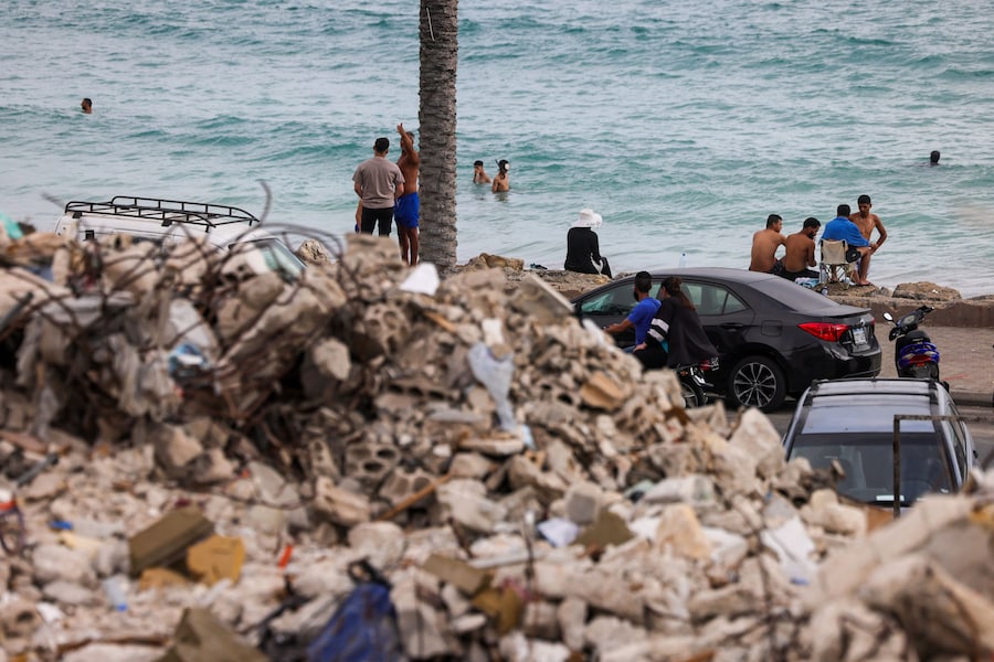Le persone che sono tornate a casa dopo essere state sfollate durante la guerra, in seguito all'accordo tra Israele e Libano, si rilassano sugli scogli lungo il lungomare di Tiro, nel sud del Libano. (REUTERS/Zohra Bensemra)