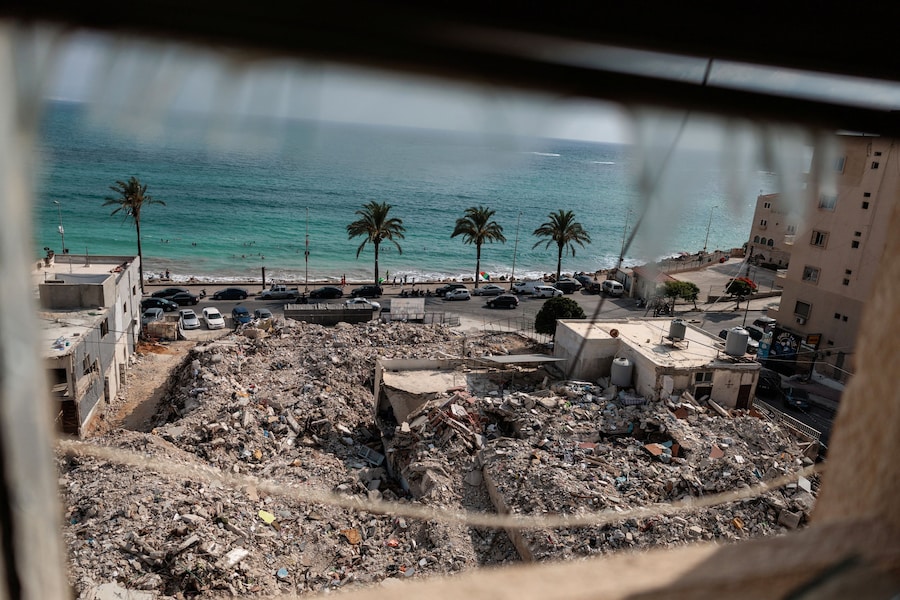 Alcune persone, tornate a casa dopo essere state sfollate durante la guerra, nuotano davanti alle macerie degli edifici distrutti dai bombardamenti israeliani a Tiro, nel sud del Libano. (REUTERS/Zohra Bensemra)