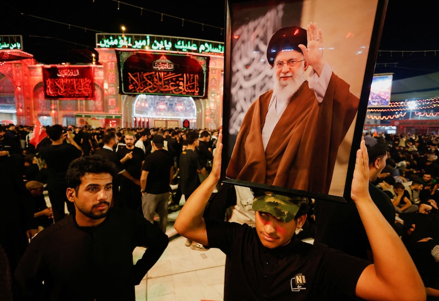 Un uomo tiene in mano un ritratto del defunto leader supremo iraniano, l’ayatollah Ali Khamenei, ucciso il 28 febbraio in seguito a attacchi aerei israeliani e statunitensi, mentre la folla si raduna per il corteo funebre a Karbala, in Iraq, il 9 luglio 2026. (REUTERS/Khalid Al-Mousily)