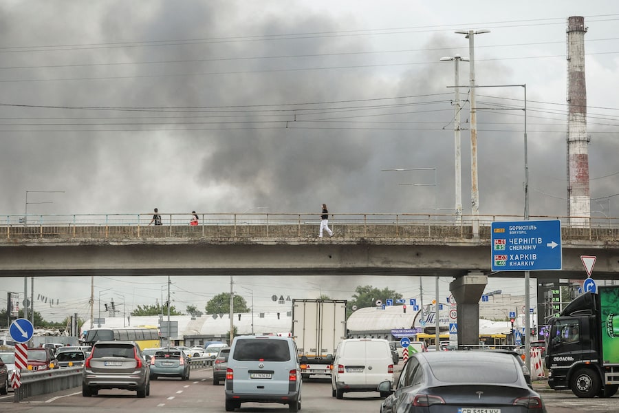 Alcune persone attraversano un ponte sopra una strada mentre il fumo si alza dal luogo colpito da un attacco con droni russi, nel contesto dell'offensiva russa contro l'Ucraina, a Kiev, Ucraina, l'8 luglio 2026. REUTERS/Alina Smutko (REUTERS)