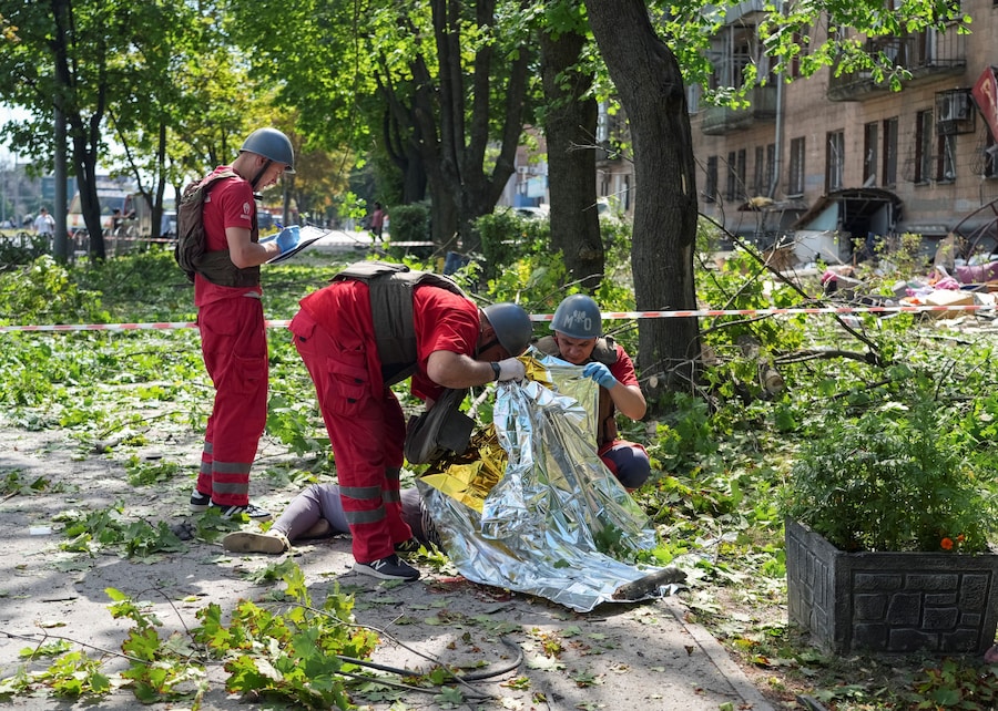 Operatori sanitari ispezionano il corpo di un residente ucciso sul luogo di un attacco missilistico russo, a Kharkiv, Ucraina. (REUTERS/Vitalii Hnidyi)