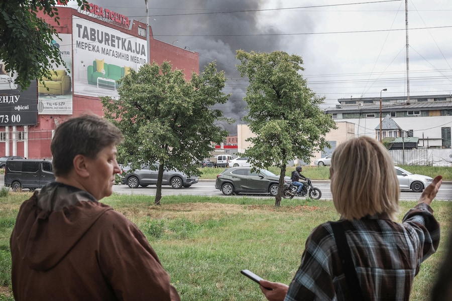 Alcuni residenti commentano in strada il fumo che si alza dal luogo colpito da un attacco con droni russi, a Kiev. (REUTERS/Alina Smutko)