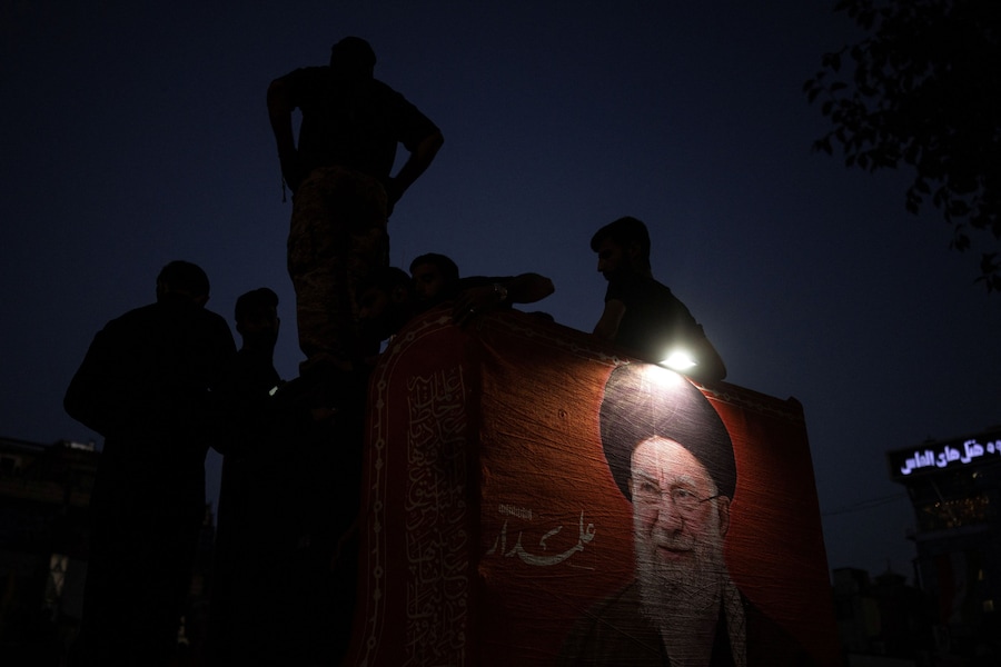 I partecipanti al funerale sono in piedi accanto a un ritratto del defunto leader supremo iraniano, l’ayatollah Ali Khamenei, ucciso il 28 febbraio in seguito a attacchi aerei israeliani e statunitensi, durante il corteo funebre nel giorno della sua sepoltura, a Mashhad, in Iran, il 9 luglio 2026. REUTERS/Alkis Konstantinidis (REUTERS)