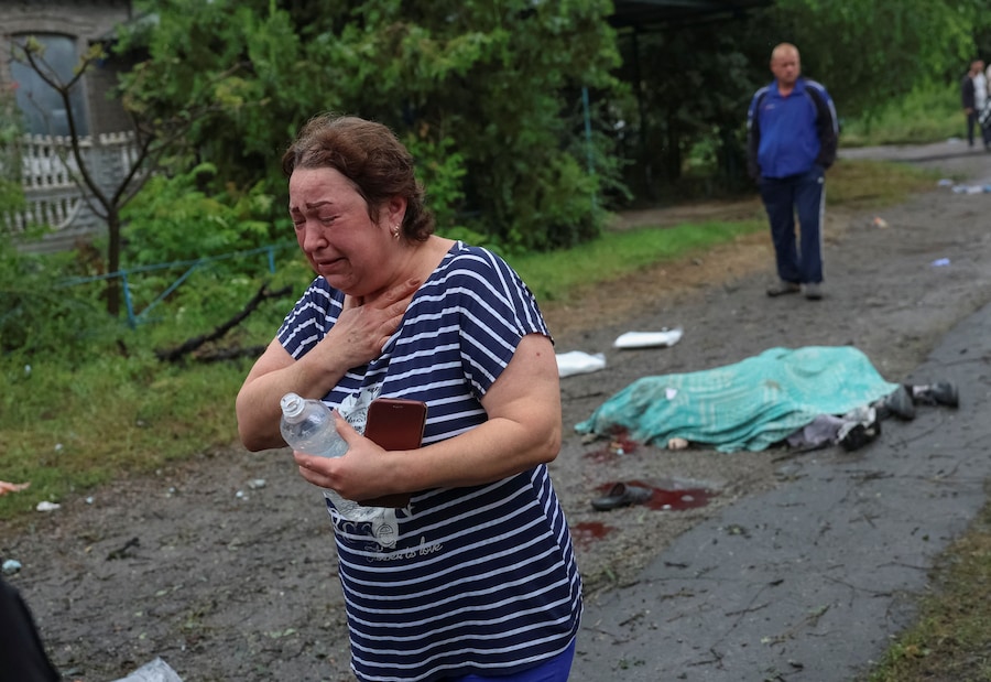 Una donna reagisce accanto ai corpi di alcuni residenti uccisi sul luogo di un attacco aereo russo, a Kramatorsk. (REUTERS/Anatolii Stepanov)