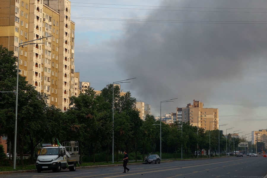 Un abitante attraversa una strada mentre il fumo si alza sopra i palazzi residenziali in seguito agli attacchi missilistici russi, nel contesto dell'offensiva russa contro l'Ucraina, a Kiev, Ucraina, l'11 luglio 2026. (REUTERS/Valentyn Ogirenko)
