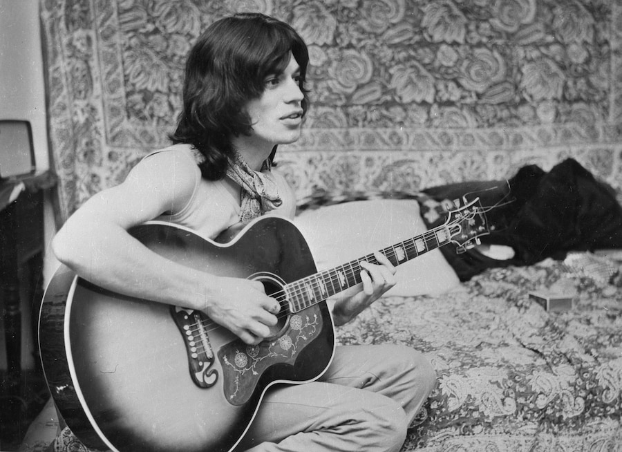 Mick Jagger, cantante della band rock britannica "The Rolling Stones", mentre suona la chitarra nel suo camerino a Londra, tra una ripresa e l'altra del film "Performance", il 25 ottobre 1968. (AP)