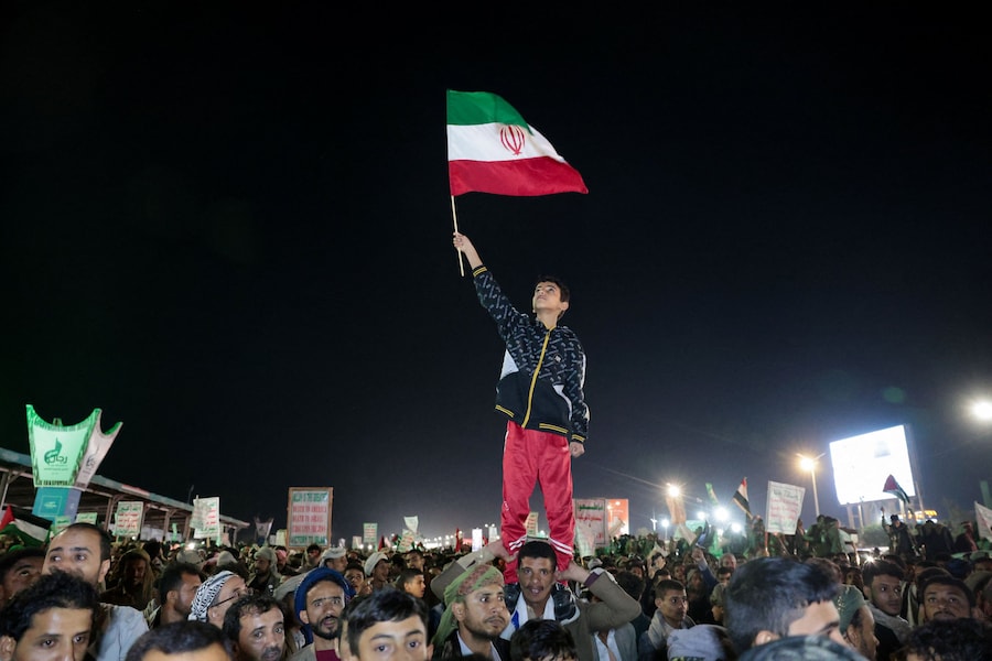 Un ragazzo sventola una bandiera iraniana mentre si unisce ai sostenitori degli Houthi che manifestano contro i raid aerei sull'aeroporto internazionale di Sanaa, a Sanaa, nello Yemen. (REUTERS)