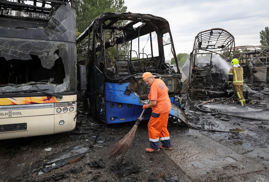 Un operatore comunale e un vigile del fuoco sono al lavoro sul luogo di un parcheggio per autobus colpito da un attacco con droni russi, nel contesto dell'offensiva russa contro l'Ucraina, a Odessa. (REUTERS)