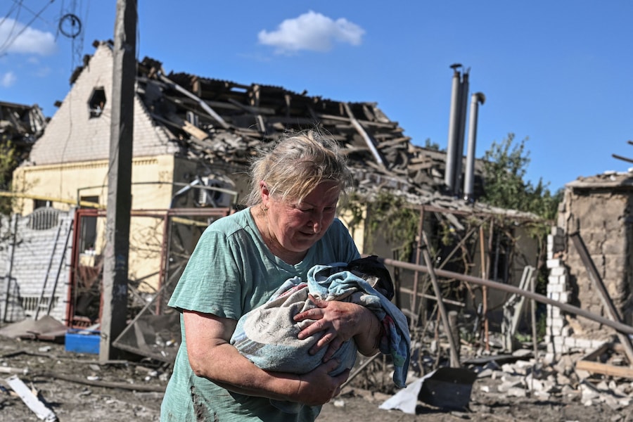 Una donna tiene in braccio un gatto, nei pressi di una casa danneggiata da un attacco aereo russo, nel contesto dell'offensiva russa contro l'Ucraina, a Zaporizhzhia. (REUTERS)