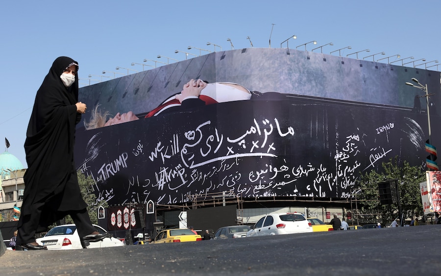 Una donna iraniana velata cammina accanto a un enorme cartellone pubblicitario che raffigura il presidente degli Stati Uniti Donald Trump in una bara, accompagnato da una frase in persiano che recita: «Uccidiamo Trump», piazza Enghelab a Teheran, in Iran, il 15 luglio 2026. (EPA)