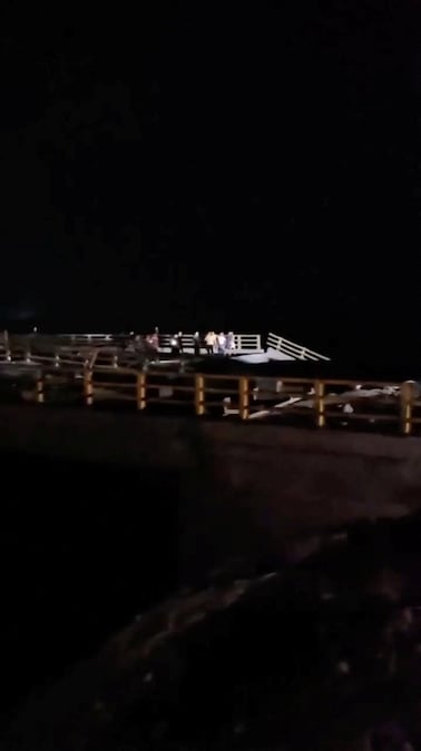 Alcune persone si trovano vicino a una sezione danneggiata di un ponte in seguito a un attacco, a Bandar Khamir (provincia di Hormozgan, Iran) (Social Media via REUTERS)