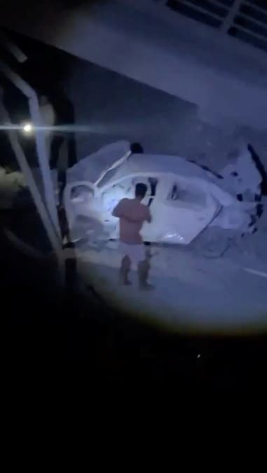 Un uomo osserva un veicolo danneggiato nei pressi di un ponte colpito, all’indomani di un attacco, a Bandar Khamir (provincia di Hormozgan, Iran) (Social Media via REUTERS)