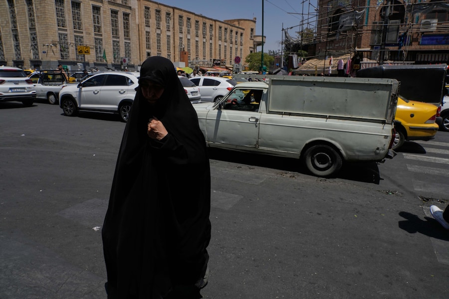 Una donna cammina mentre i veicoli transitano a un incrocio nei pressi del tradizionale bazar principale di Teheran, in Iran (APN)