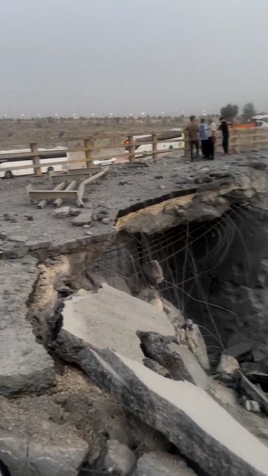 Alcune persone si trovano vicino a una sezione danneggiata di un ponte in seguito a un attacco, a Bandar Khamir (provincia di Hormozgan, Iran) (Social Media via REUTERS)