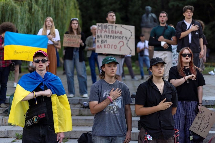 La gente canta l'inno nazionale durante una manifestazione di protesta contro la decisione del presidente ucraino Volodymyr Zelenskiy di sostituire Mykhailo Fedorov alla carica di ministro della Difesa, mentre la Russia continua ad attaccare l'Ucraina, a Kiev, Ucraina, il 16 luglio 2026. (REUTERS)