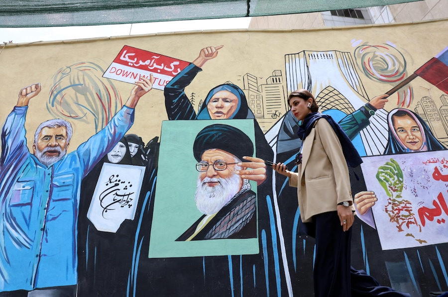Una donna cammina accanto a un murale anti-statunitense in una strada di Teheran, in Iran. (EPA/Abedin Taherkenareh)