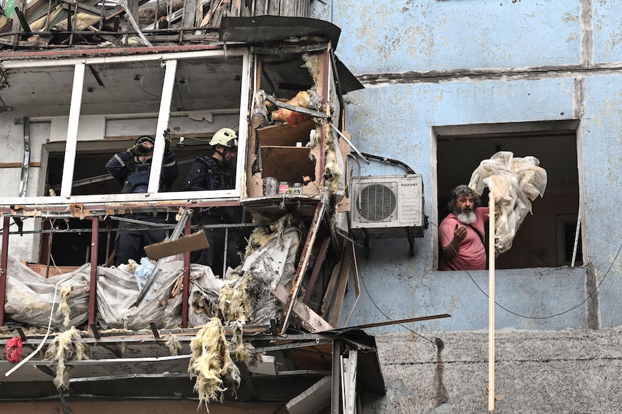 Un residente e alcuni soccorritori rimuovono le macerie sul luogo di un condominio danneggiato durante un attacco aereo russo, nel contesto dell'offensiva russa contro l'Ucraina, a Zaporizhzhia. (REUTERS)