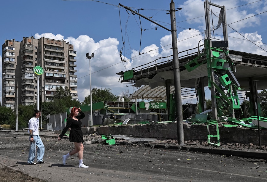 Alcuni residenti camminano nei pressi di una stazione di servizio colpita da un attacco aereo russo, a Zaporizhzhia. (REUTERS/Stringer)