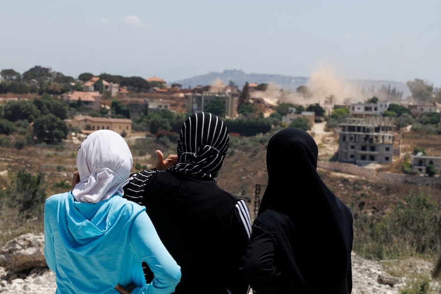 Alcuni residenti, impossibilitati a rientrare nelle proprie abitazioni situate in un’area dove operano ancora i soldati israeliani, osservano la polvere sollevata dai carri armati israeliani in azione nel villaggio di Zawtar al-Sharqiya; si trovano a Zawtar al-Gharbiyeh, nel Libano meridionale (REUTERS)