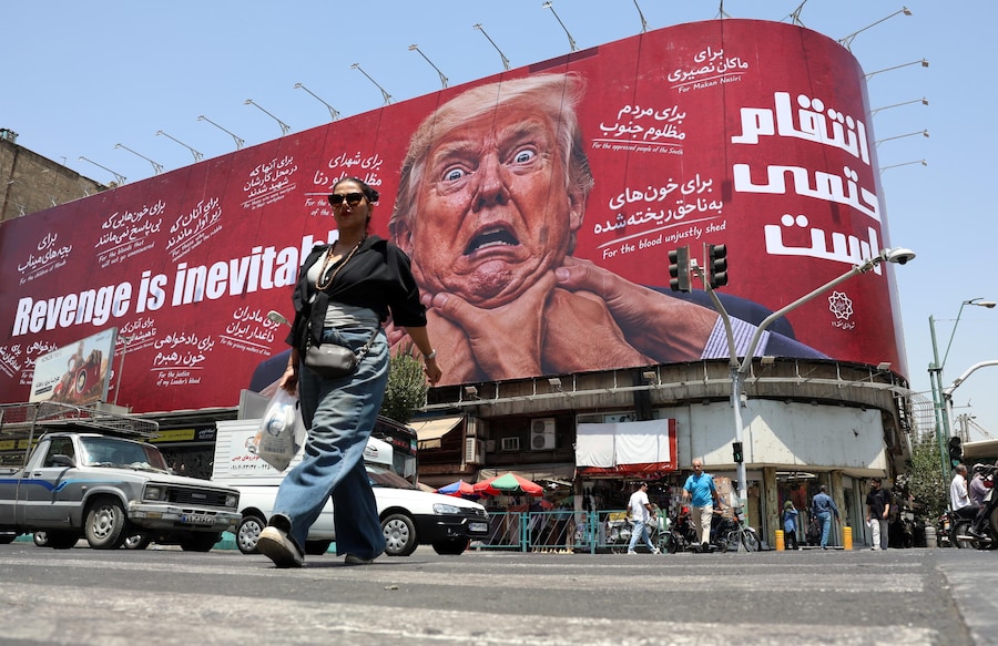 Una donna passa davanti a un cartellone contro gli Stati Uniti e Trump in una strada di Teheran, Ira (EPA)