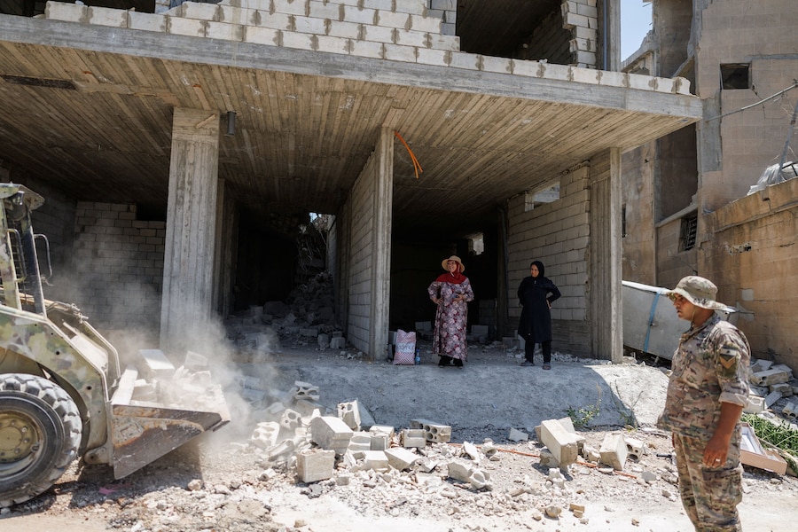 Heba Khalil Turkiyeh e Haifa Shkair osservano i soldati dell’esercito libanese mentre sgomberano la strada dalle macerie di edifici danneggiati dai raid israeliani, proprio davanti alle loro abitazioni; le due donne sono rientrate a Zawtar al-Gharbiyeh, un villaggio nel sud del Libano (REUTERS)
