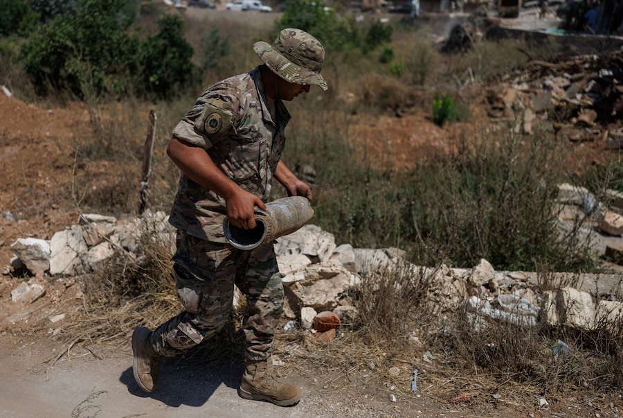 Un ufficiale dell’esercito libanese trasporta un bossolo vuoto rinvenuto in un campo appartenente a un agricoltore; quest’ultimo ha riferito che il terreno era stato spianato dai bulldozer dell’esercito israeliano a Zawtar al-Gharbiyeh, un villaggio nel Libano meridionale (REUTERS)