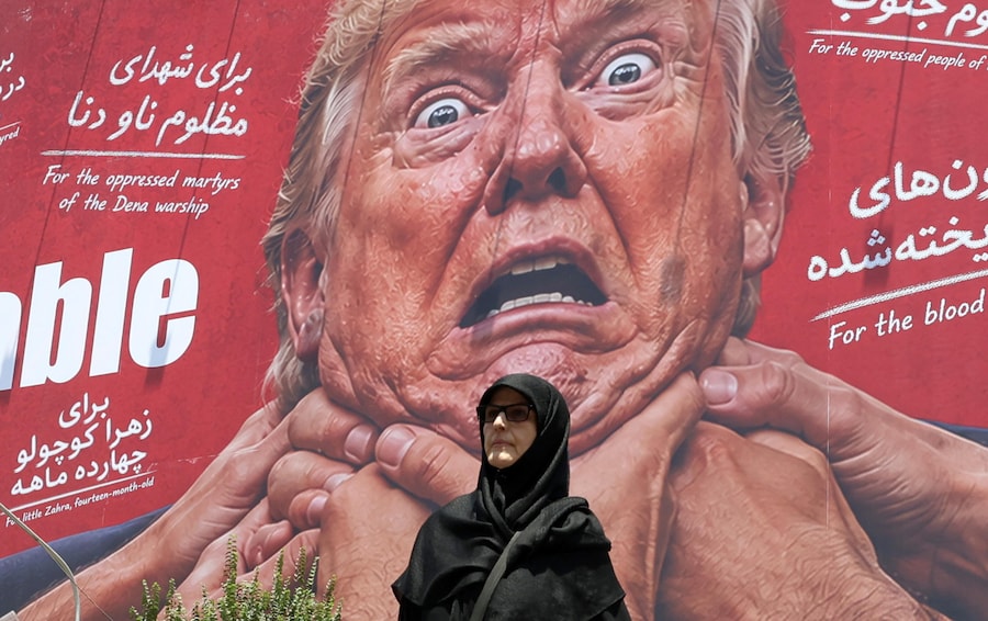 Una donna passa davanti a un cartellone contro gli Stati Uniti e Trump in una strada di Teheran, Iran (EPA)
