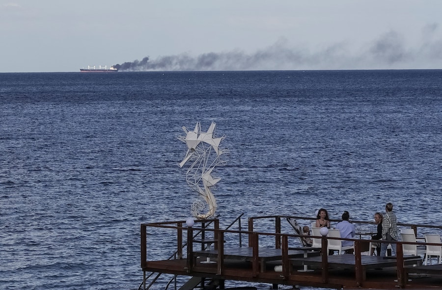 Ad Odessa, in Ucraina, il 28 luglio 2026, alcune persone sono sedute in un bar mentre il fumo si alza da un’imbarcazione civile in fiamme, nel contesto dell’attacco della Russia all’Ucraina. REUTERS/Nina Liashonok (REUTERS)