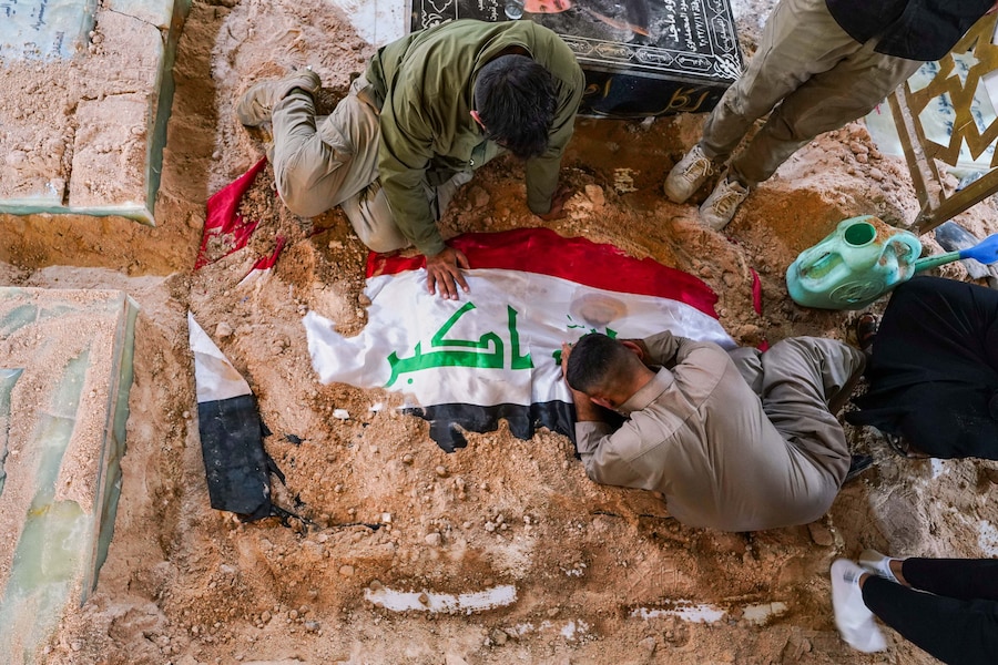 Alcune persone piangono sulla tomba di un combattente delle Forze di Mobilitazione Popolare durante i funerali dei combattenti rimasti uccisi in attacchi aerei contro le basi delle PMF a Najaf, in Iraq (APN)