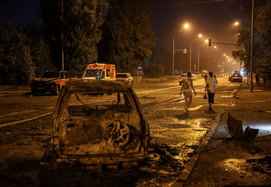 Alcuni residenti lasciano il luogo colpito da un missile russo durante l’attacco della Russia all’Ucraina, nella regione di Kiev (REUTERS)