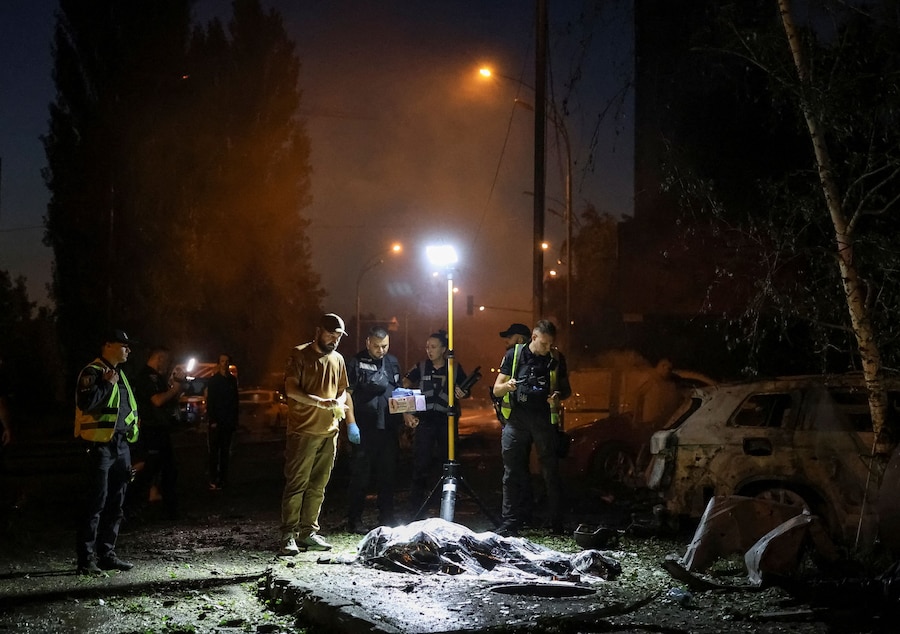 Agenti di polizia lavorano vicino al corpo di un residente rimasto ucciso nel luogo di un attacco missilistico russo a Kiev (REUTERS)