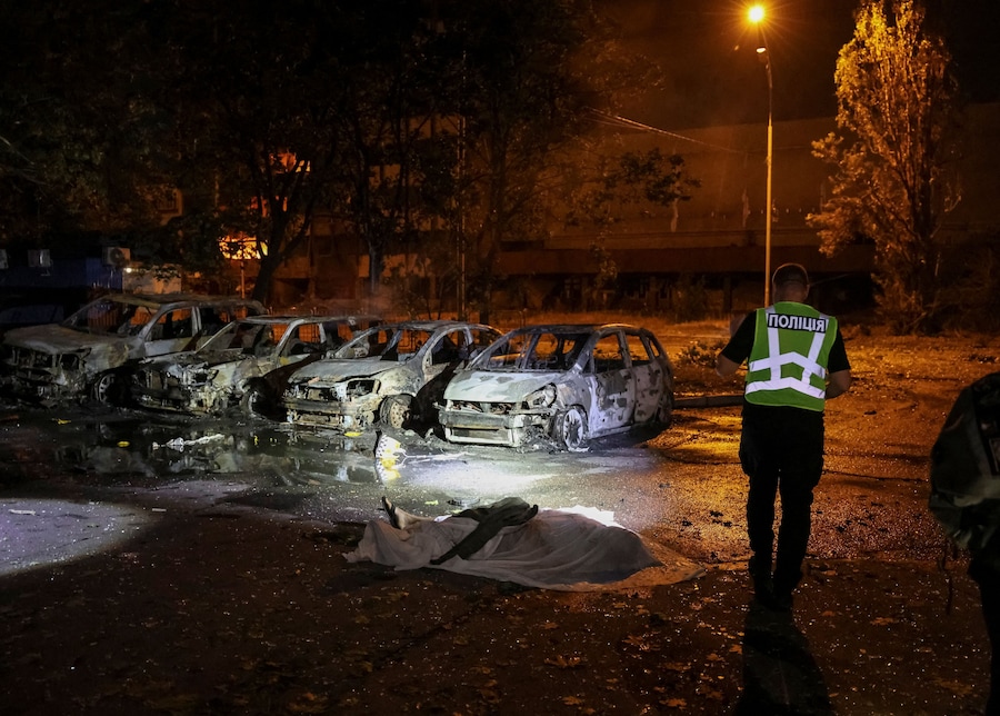 Un agente di polizia si trova vicino al corpo di un residente rimasto ucciso nel luogo di un attacco missilistico russo nella regione di Kiev (REUTERS)