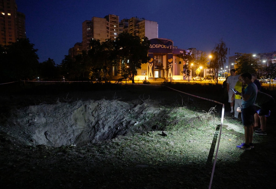 Residenti osservano un cratere nel luogo colpito da un missile russo in una zona residenziale di Kiev (EPA)
