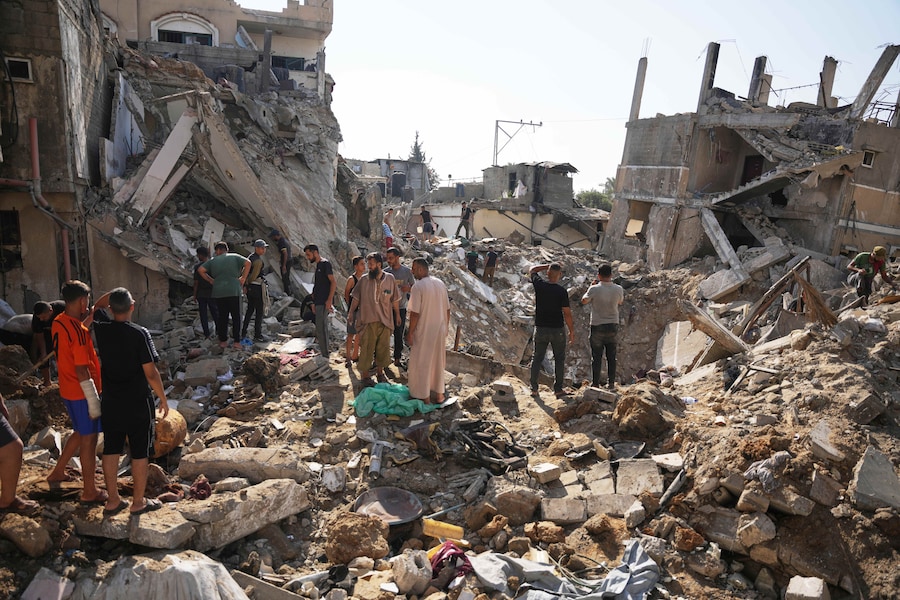 Dei palestinesi esaminano gli edifici distrutti sul luogo di un attacco aereo israeliano nel campo profughi di al-Maghazi, nella Striscia di Gaza centrale (APN)