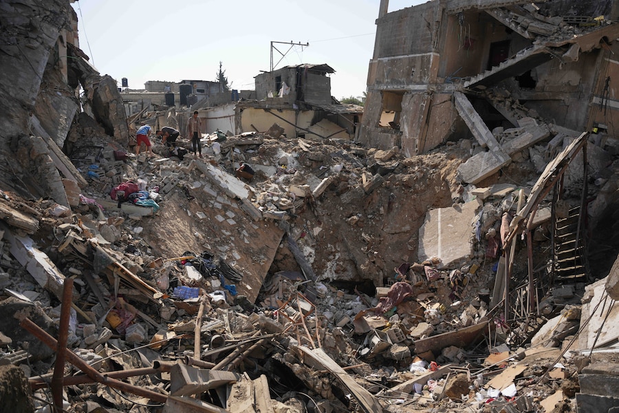 Dei palestinesi recuperano i propri averi dagli edifici distrutti nel luogo colpito da un attacco aereo israeliano, nel campo profughi di al-Maghazi, nella Striscia di Gaza centrale (APN)