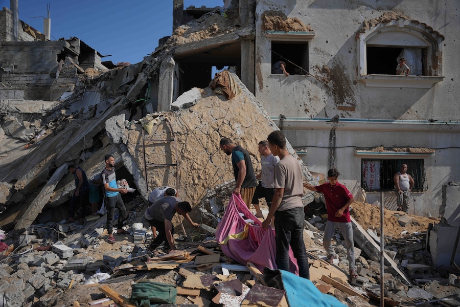 Dei palestinesi recuperano i propri averi dagli edifici distrutti sul luogo di un attacco aereo israeliano, nel campo profughi di al-Maghazi, nella Striscia di Gaza centrale (APN)