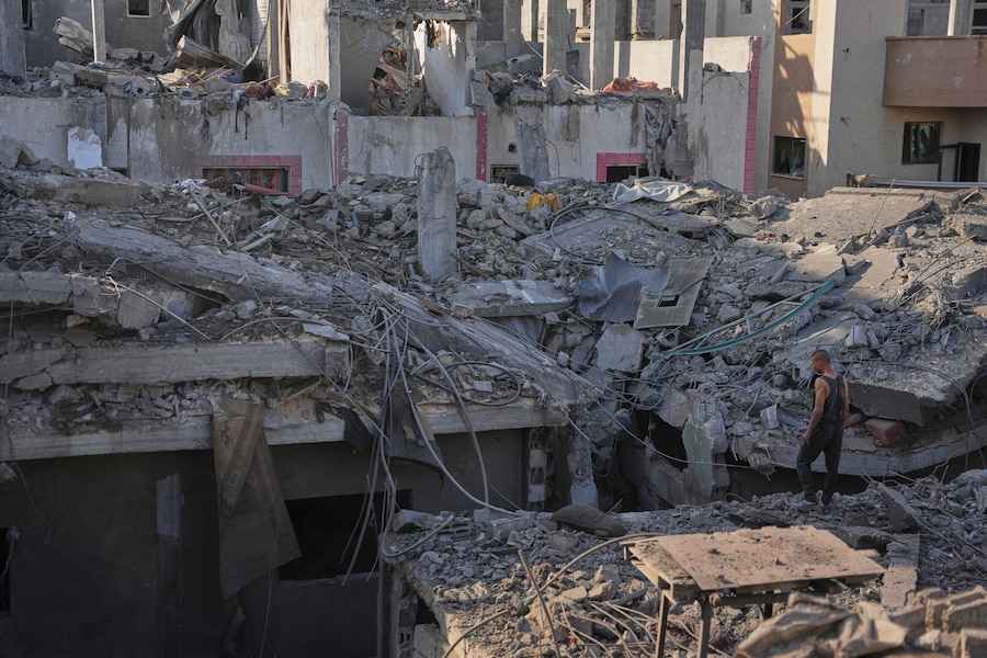 Alcuni palestinesi esaminano gli edifici distrutti sul luogo di un attacco aereo israeliano a Nuseirat, nella Striscia di Gaza centrale (APN)