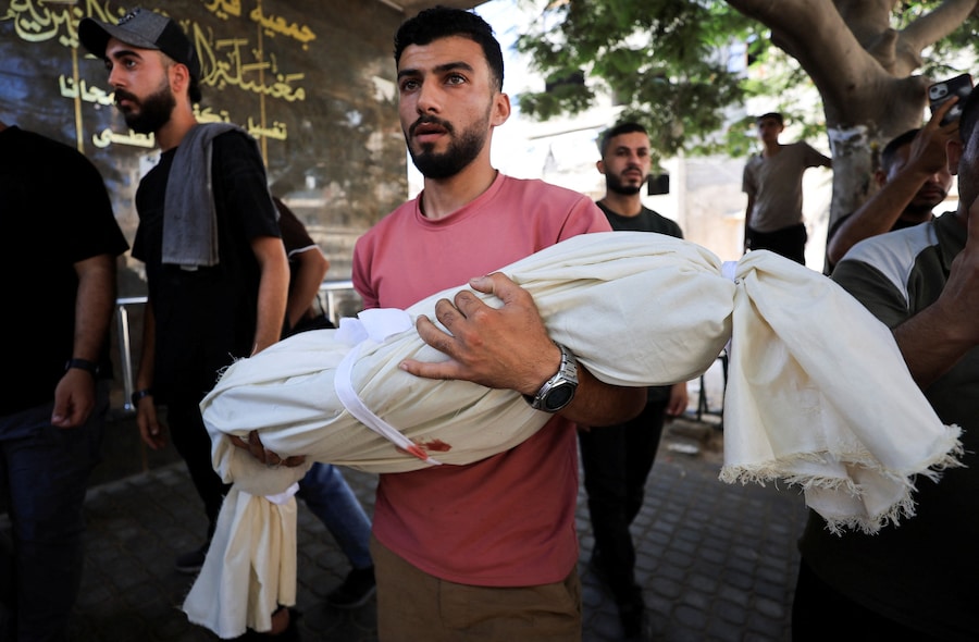 Una persona in lutto trasporta il corpo di un palestinese rimasto ucciso in attacchi israeliani – secondo quanto riferito dai sanitari – durante un funerale a Gaza City (REUTERS)
