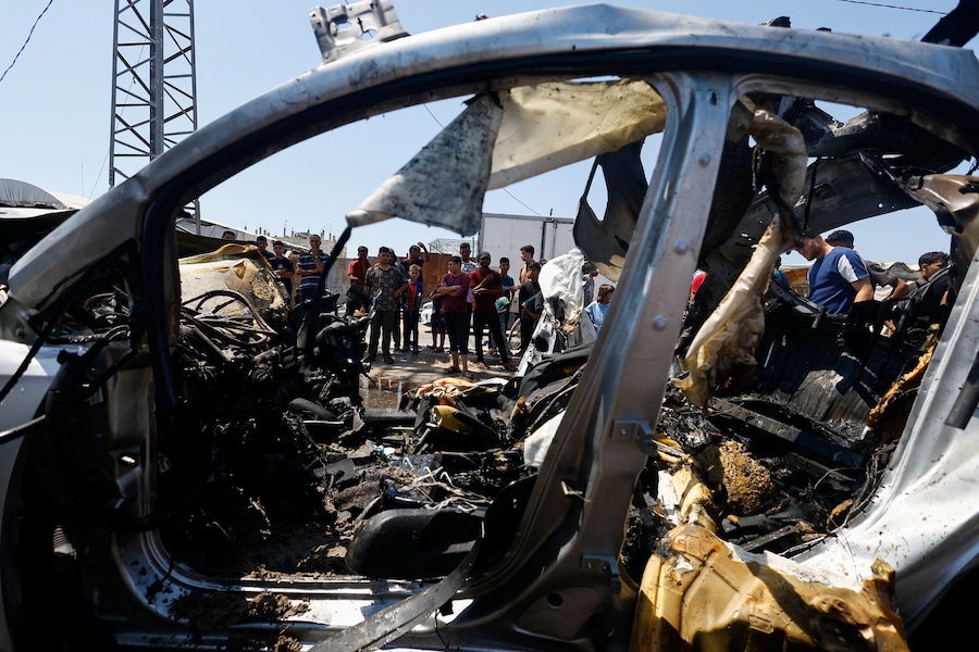 Alcuni palestinesi esaminano il luogo di un attacco israeliano contro un veicolo – secondo quanto riferito dai soccorritori – a Deir al-Balah, nella Striscia di Gaza centrale (REUTERS)