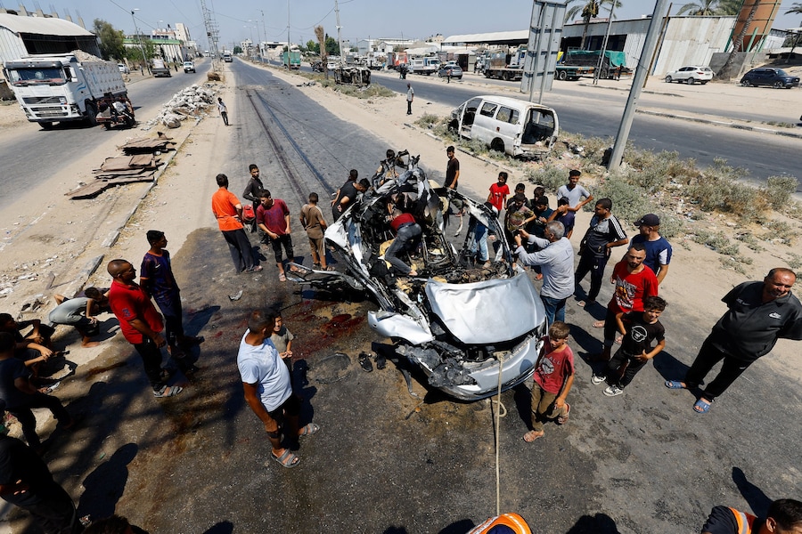 Alcuni palestinesi esaminano il luogo di un attacco israeliano contro un veicolo – secondo quanto riferito dai soccorritori – a Deir al-Balah, nella Striscia di Gaza centrale (REUTERS)