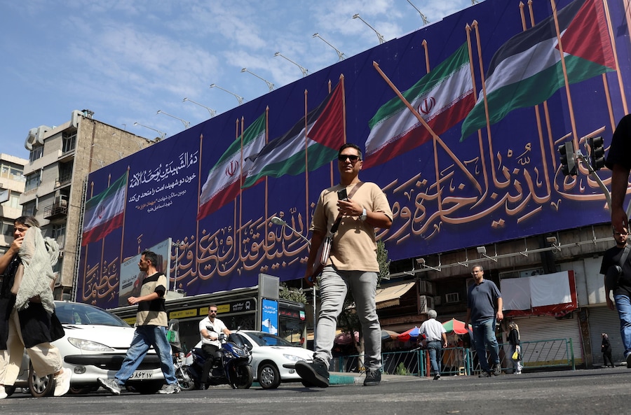 Alcuni iraniani passano davanti a un cartellone pubblicitario su cui sono raffigurate le bandiere dell’Iran e della Palestina in una strada di Teheran, in Iran. Le tensioni tra l’Iran e gli Stati Uniti sullo Stretto di Ormuz continuano dopo che il presidente degli Stati Uniti Donald Trump ha segnalato la possibilità di ulteriori attacchi statunitensi contro l’Iran. (EPA/Abedin Taherkenareh)