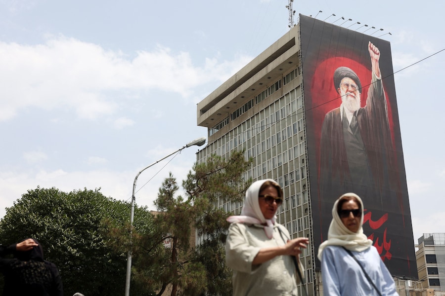 Alcune persone camminano vicino a un cartellone pubblicitario raffigurante il defunto leader supremo iraniano, l'ayatollah Ali Khamenei, in una strada di Teheran, in Iran. (Majid Asgaripour/WANA (West Asia News Agency) via REUTERS)