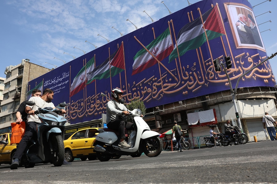 Alcuni automobilisti iraniani passano davanti a un cartellone pubblicitario su cui sono raffigurate le bandiere dell’Iran e della Palestina e i ritratti del defunto leader supremo iraniano, l’ayatollah Ali Khamenei, e del defunto leader di Hamas, Ismail Haniyeh, in una strada di Teheran. (EPA/Abedin Taherkenareh)